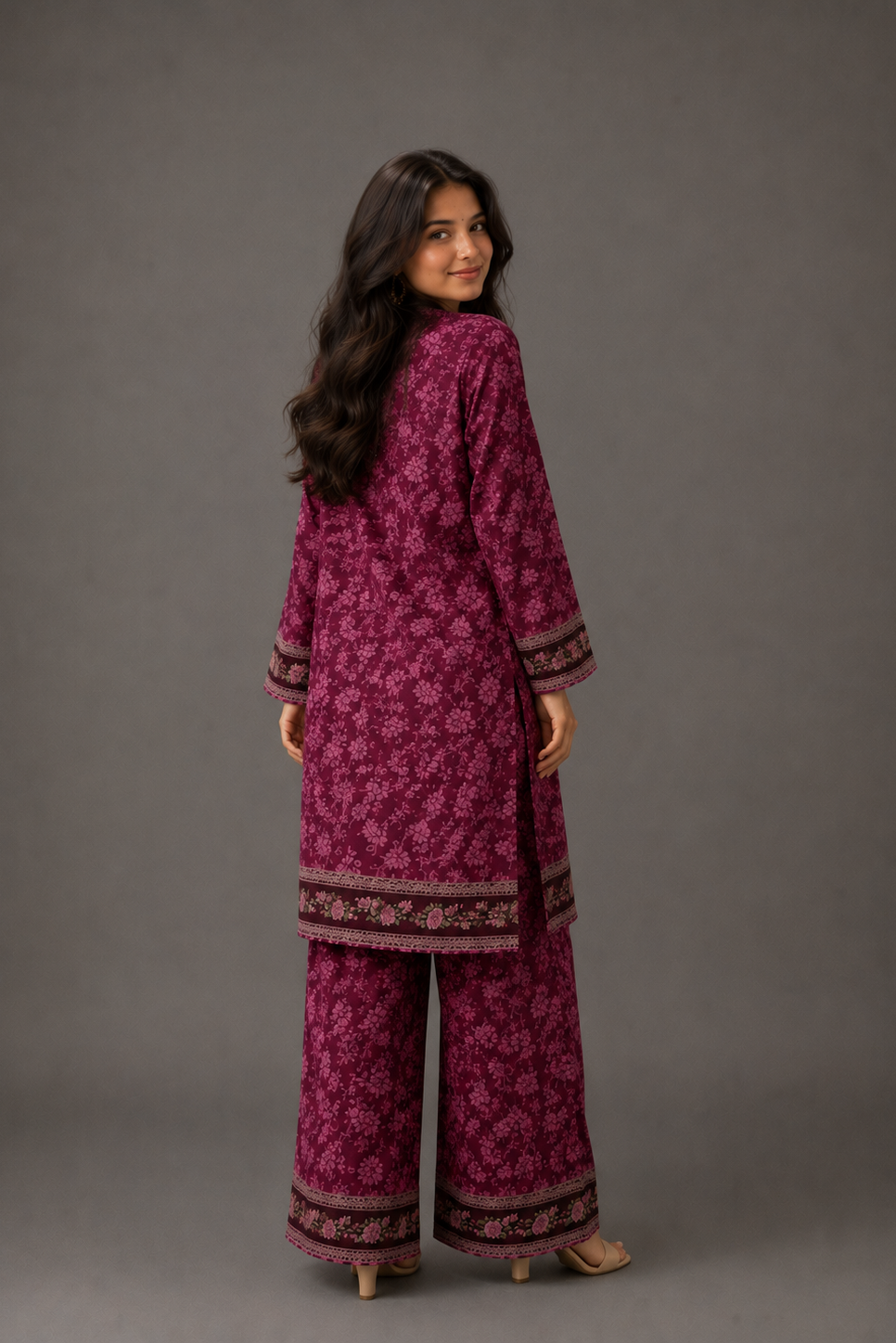 Woman wearing a magenta patterned outfit against a gray background
