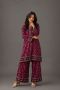 Woman wearing a purple patterned outfit against a gray background
