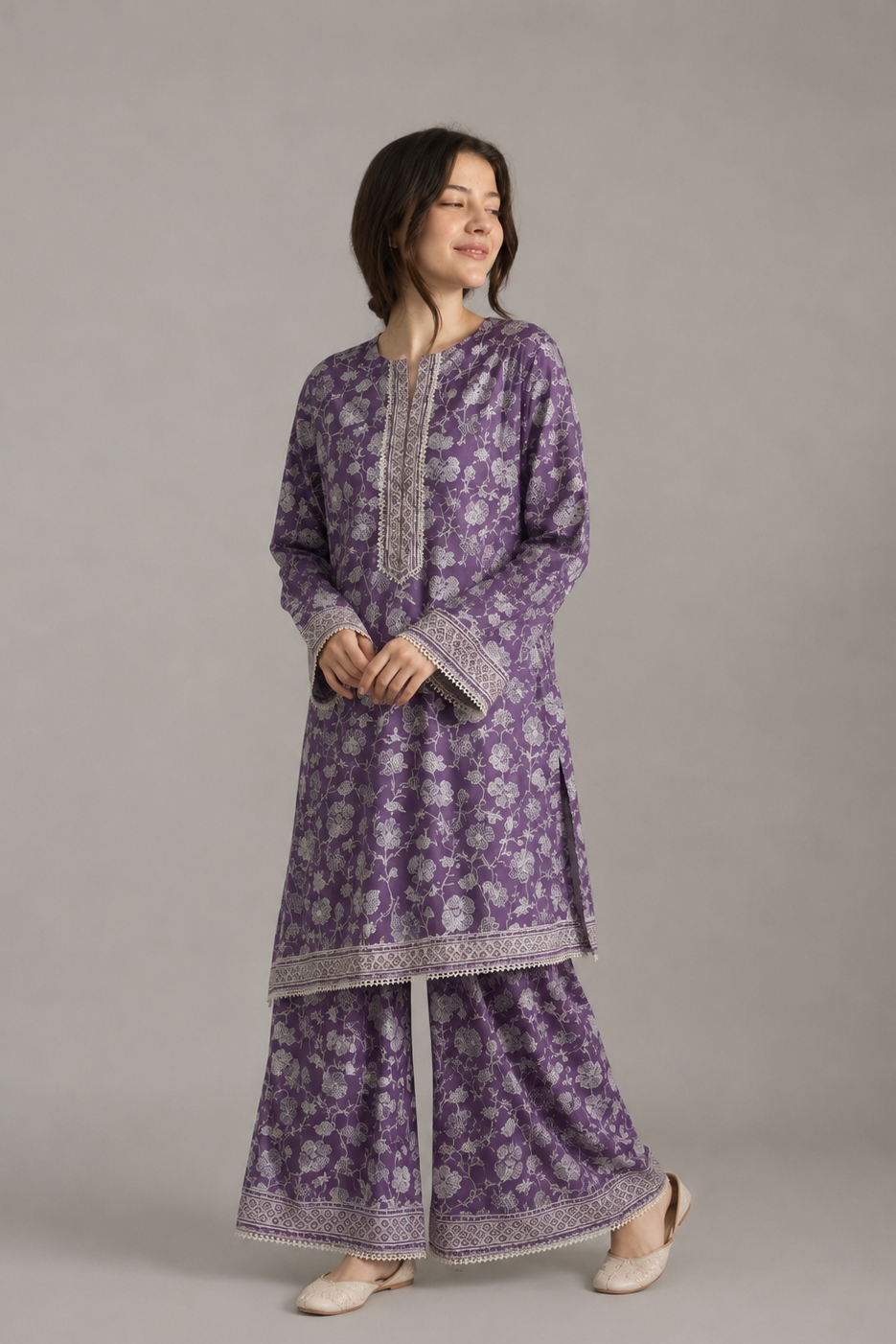 Woman wearing a purple floral outfit with intricate patterns on a plain background