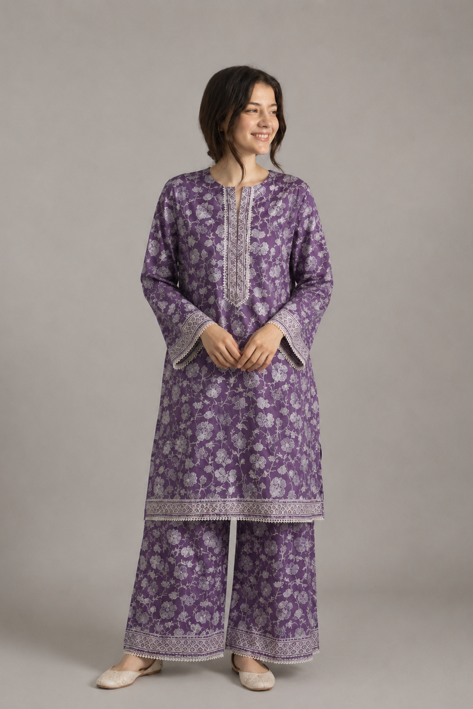 Woman wearing a purple floral kurta with white embroidery on a gray background