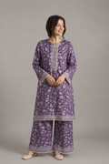 Woman wearing a purple floral kurta with white embroidery on a gray background