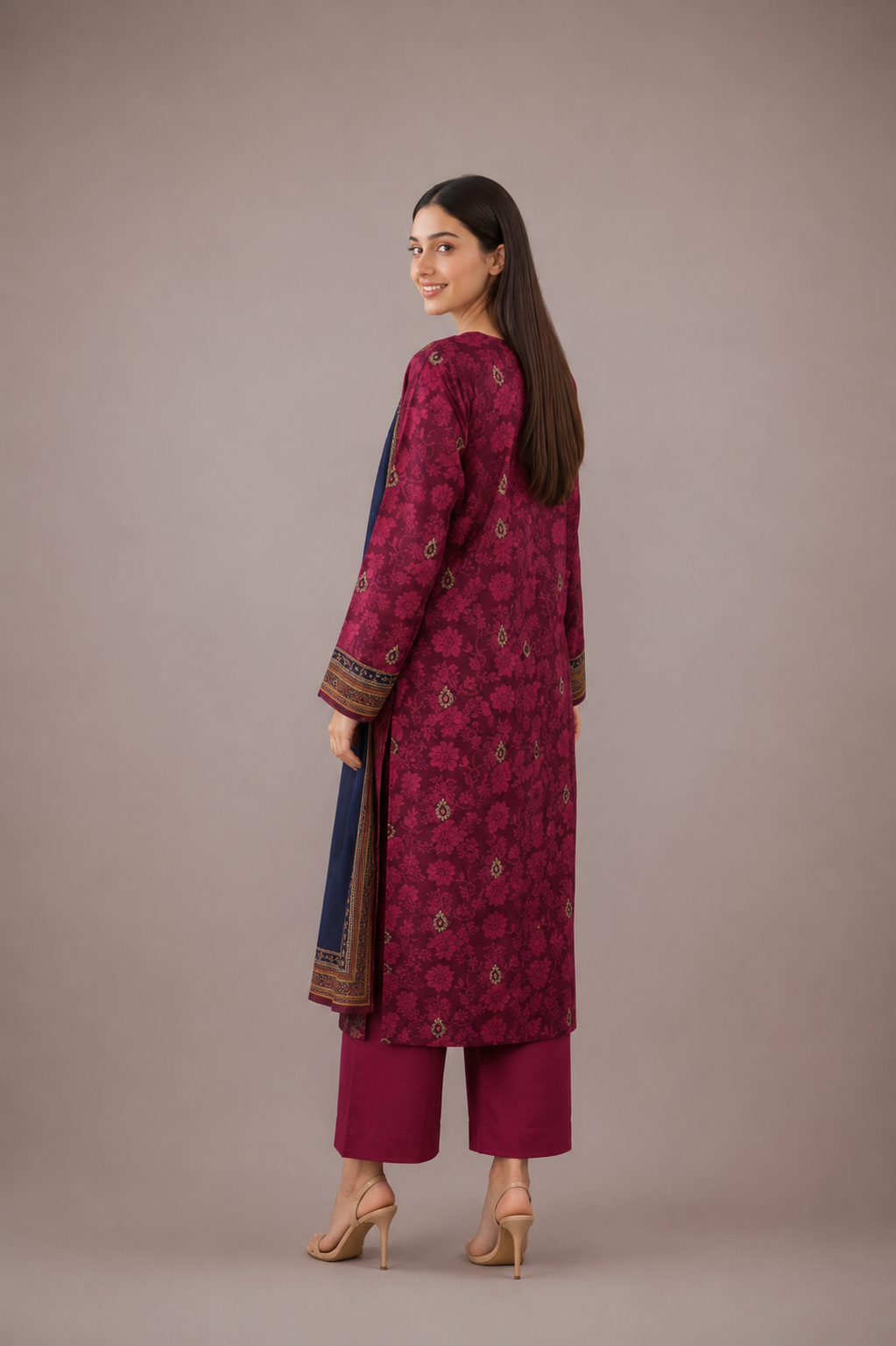 Woman wearing a maroon traditional outfit with a patterned top and matching pants on a beige background