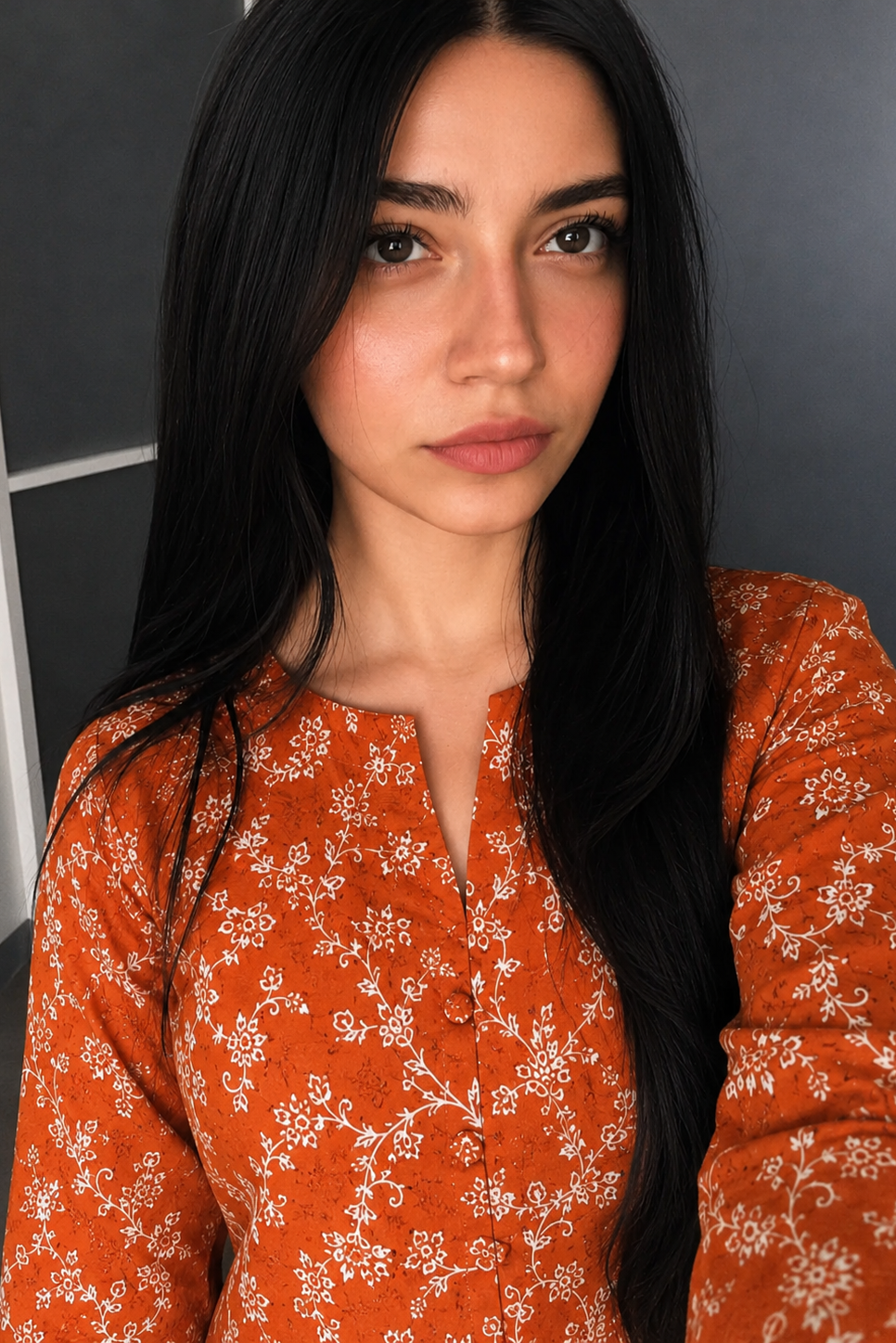 Woman wearing an orange floral blouse against a dark background