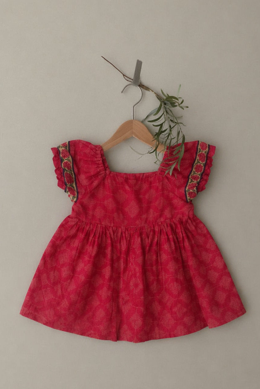 Red patterned dress on a hanger against a plain background