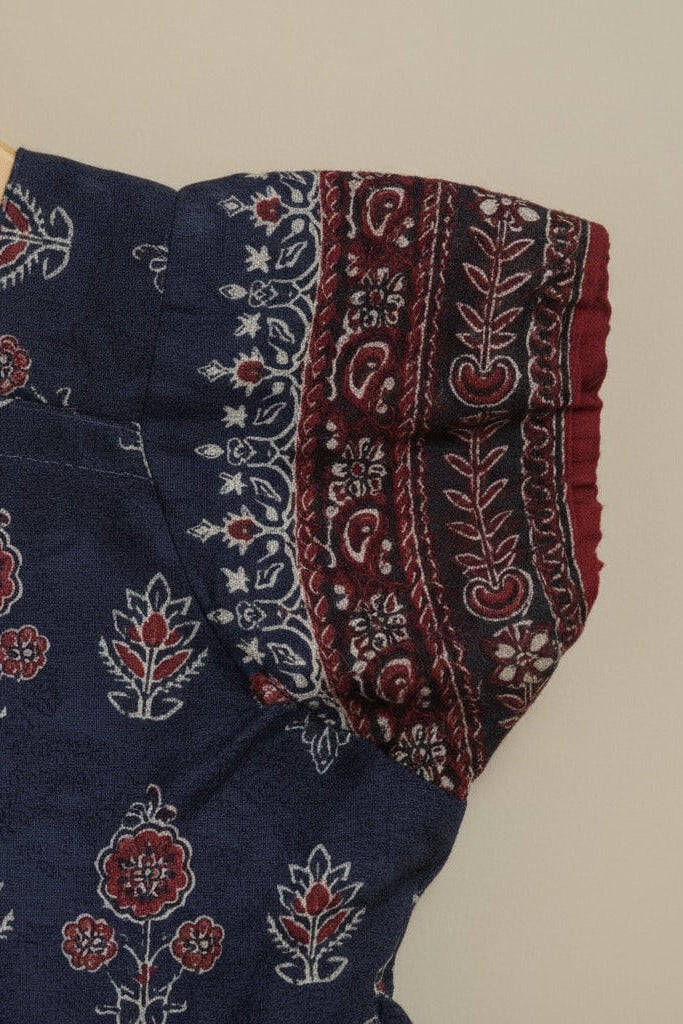 Navy blue dress with red and white floral patterns on a beige background