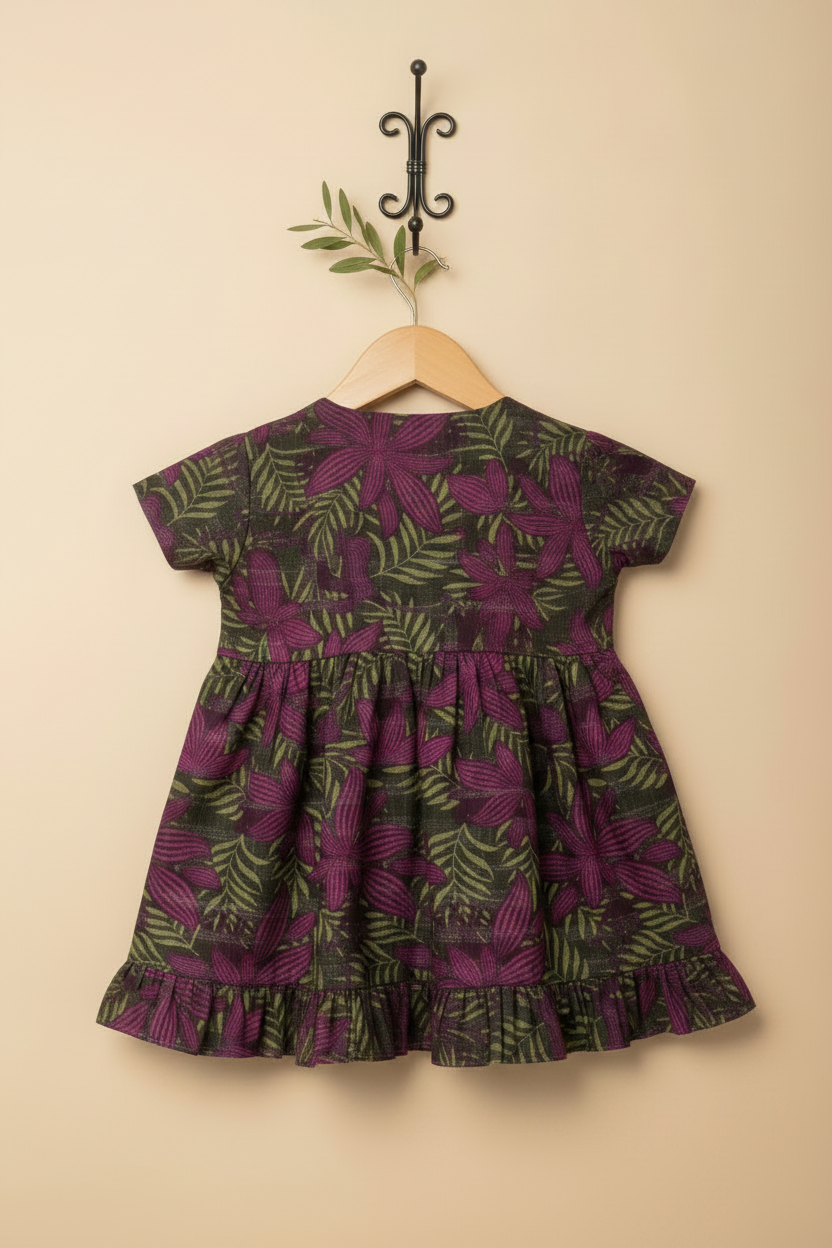 Purple and green patterned dress on a hanger against a beige wall