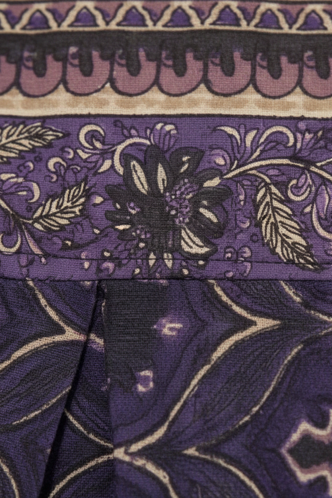Close-up of a purple fabric with intricate patterns and floral designs.