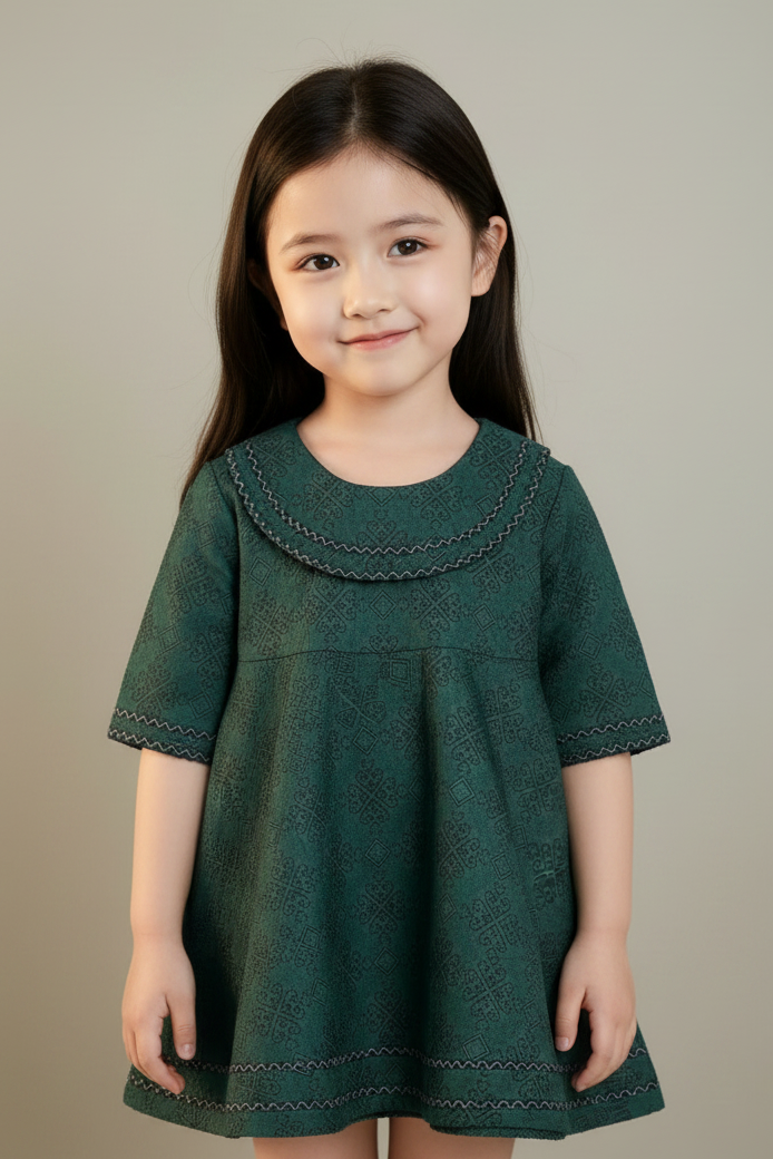 Young girl wearing a green dress against a plain background