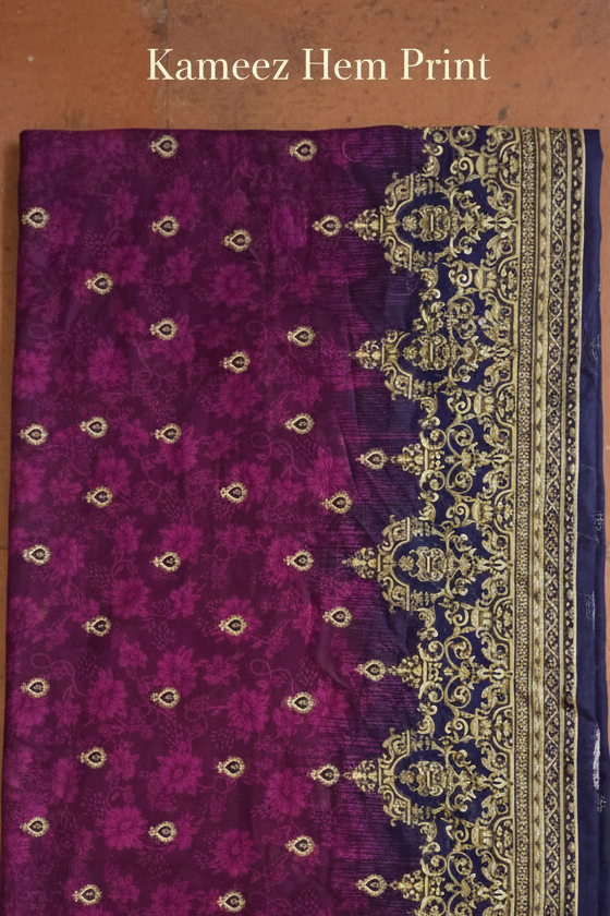 Purple fabric with intricate gold and blue patterns on a brown surface