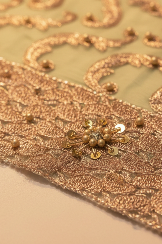 Close-up of a gold lace fabric with sequins on a beige background