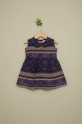Purple patterned dress on a hanger against a beige wall