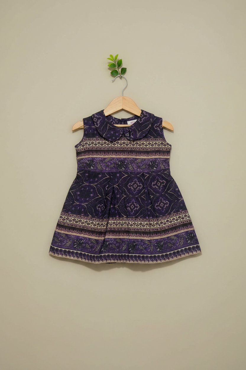 Purple patterned dress on a hanger against a beige wall